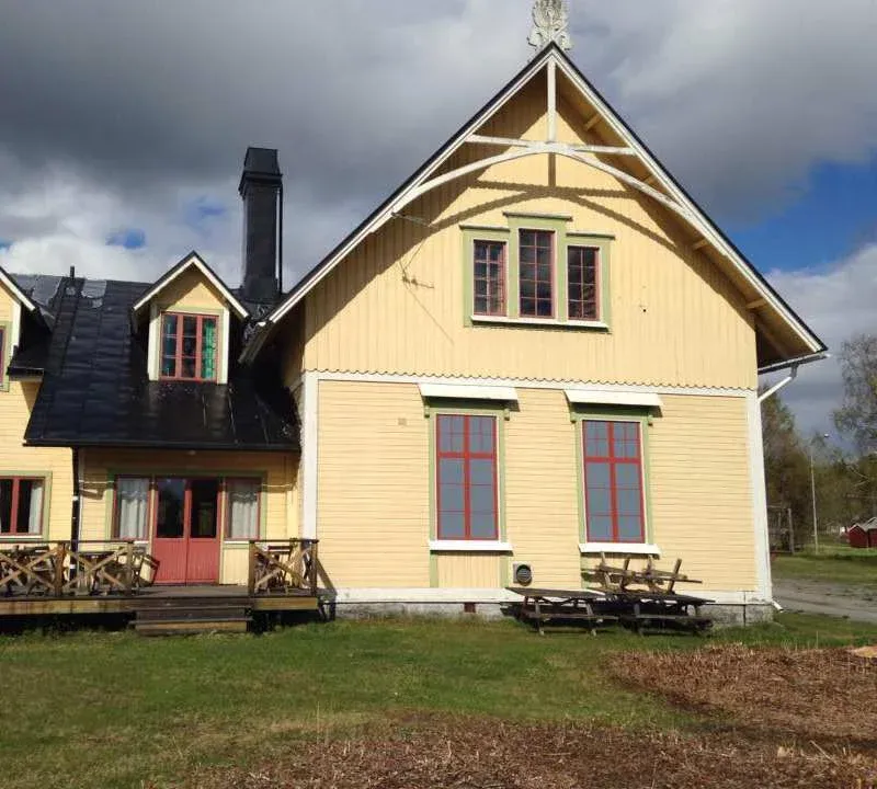 Hägragårdens gula träbyggnad med altan en vårdag